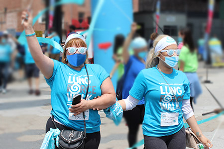 two women waving ribbons at a LUNG FORCE Walk